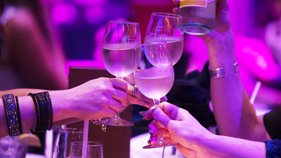 Three friends toasting with glasses of white wine in a festive atmosphere in close-up.