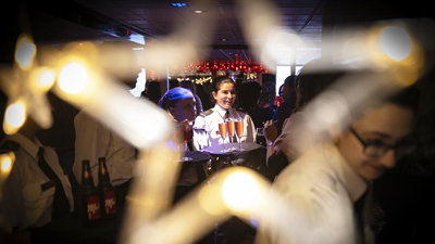 Waitress holding a tray with glasses of sparkling rosé wine with a star-shaped Christmas decoration in the foreground framing the scene