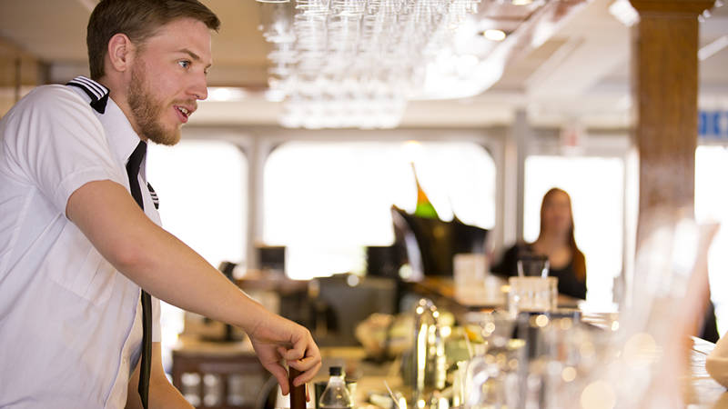 Serveur en train de servir une boisson à un client à bord du AML Louis Jolliet à Québec