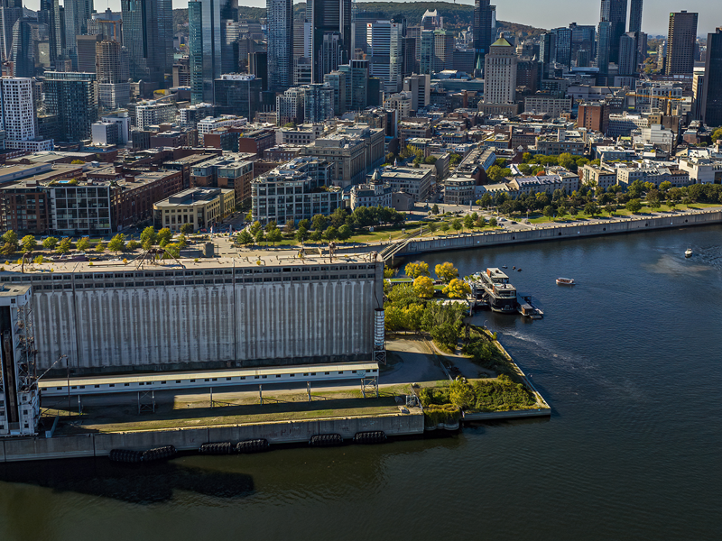 Aerial view of the AML Cavalier Maxim ship leaving the Old Port of Montreal, with a view of the city in the background under a blue sky.