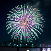 Large and vibrant blue and pink fireworks in Montreal with the shadow of the Jacques Cartier Bridge below