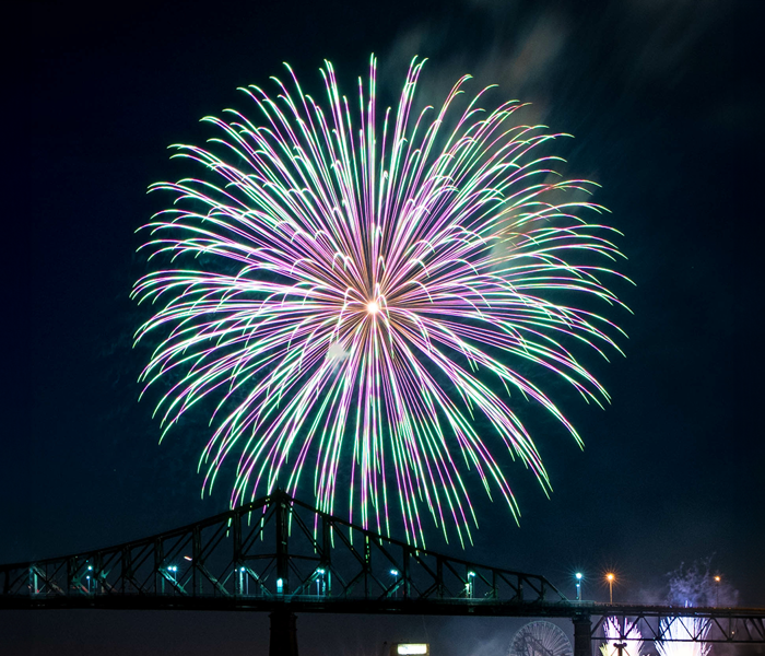 Gros feux d'artifice époustouflant bleu et rose à Montréal avec l'ombre du pont Jacques Cartier en-dessous