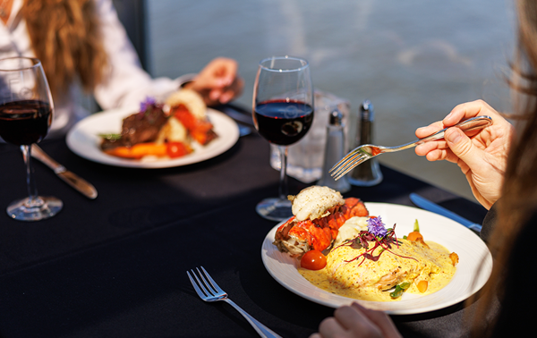 Plate containing a bistronomic meal of grilled meat with fresh market vegetables accompanied by a glass of red wine