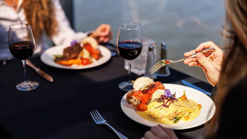 Assiette comprenant un repas bistronomique de viande grillée avec des légumes frais du marché accompagné d'un verre de vin rouge