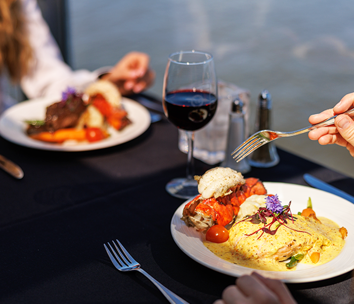 Assiette comprenant un repas bistronomique de viande grillée avec des légumes frais du marché accompagné d'un verre de vin rouge