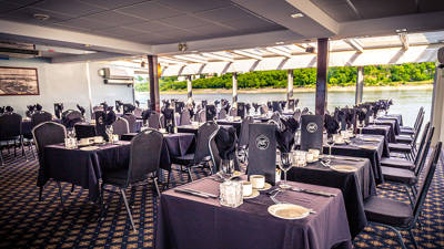 Une salle de restaurant du navire AML Louis Jolliet avec des tables dressées et une vue imprenable sur le fleuve Saint-Laurent à Québec