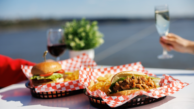 Vue d'un repas avec des hamburgers et des frites servis dans des paniers sur une table sur l'une des terrasses du navire AML Cavalier Maxim de Montréal.