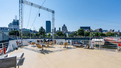 View of the front outdoor terrace of the AML Cavalier Maxim boat with the city of Montreal in the background.