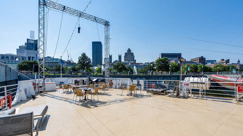 Vue sur la terrasse extérieure avant du bateau AML Cavalier Maxim avec la ville de Montréal en arrière plan