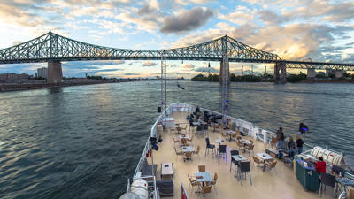 Vue depuis la terrasse extérieure avant du navire AML Cavalier Maxim avec en arrière plan un panorama sur le fleuve Saint-Laurent et la ville de Montréal