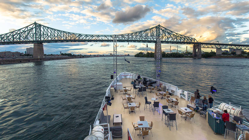 Vue depuis la terrasse extérieure avant du navire AML Cavalier Maxim avec en arrière plan un panorama sur le fleuve Saint-Laurent et la ville de Montréal