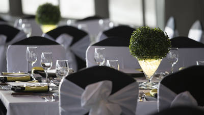 Close-up of the dining room with set and decorated tables. Each table is also adorned with plates, glasses, and folded napkins