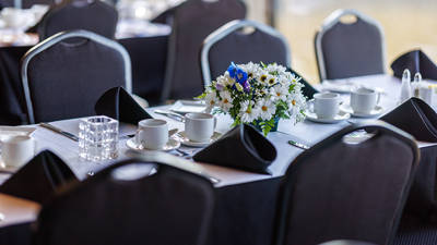 Close-up of a set table, with plates, glasses, cutlery, and a beautiful white and blue bouquet as decoration.