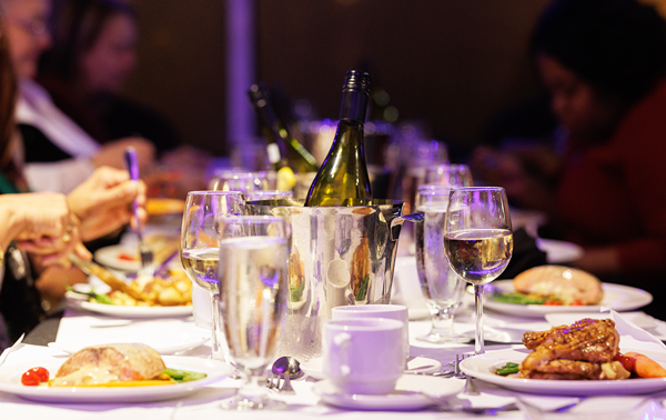 Gros plan sur une table d'un souper-croisière garnie de plats, de verres et de bouteilles de champagne et de vin.