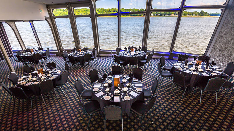 Indoor room with set tables and large bay windows overlooking the Saint Lawrence River in Quebec City