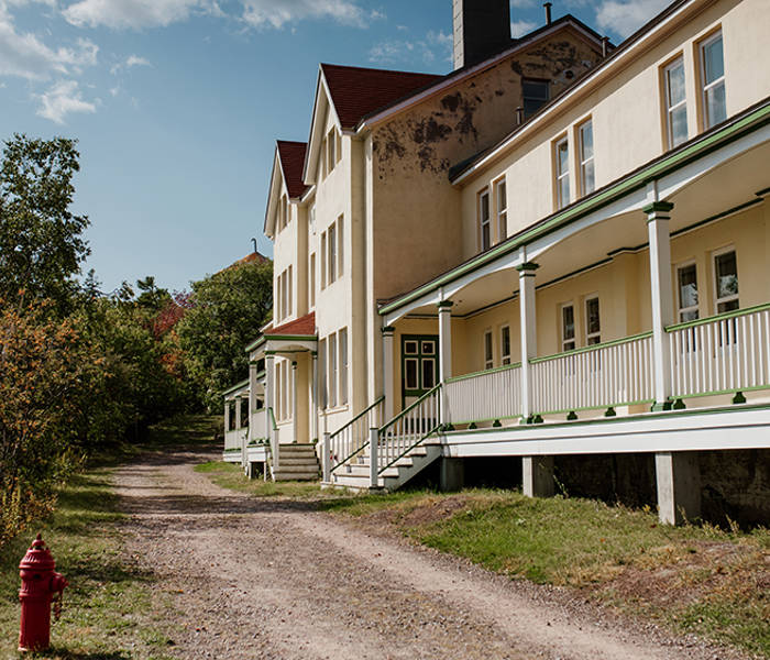 Bâtiments extérieurs de la station de quarantaine Grosse-Île avec un chemin et de la verdure. 