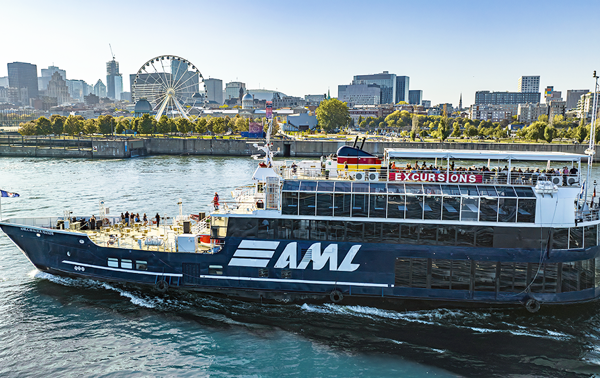 The AML Cavalier Maxim sailing on the St. Lawrence River, with the Old Port and the Montreal skyline in the background.