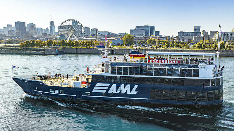 The AML Cavalier Maxim sailing on the St. Lawrence River, with the Old Port and the Montreal skyline in the background.