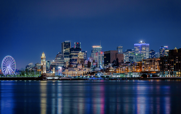 Une vue nocturne sur la skyline illuminée de Montréal depuis le Vieux Port et la grande roue.