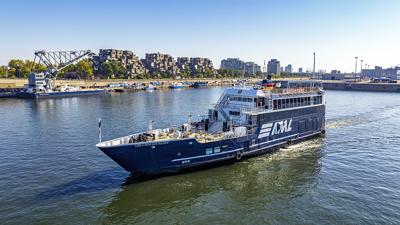 Aerial view of the AML Cavalier Maxim sailing on the St. Lawrence in Montreal, with Habitat 67 in the background.