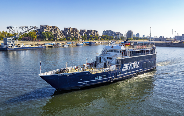 Aerial view of the AML Cavalier Maxim sailing on the St. Lawrence in Montreal, with Habitat 67 in the background.