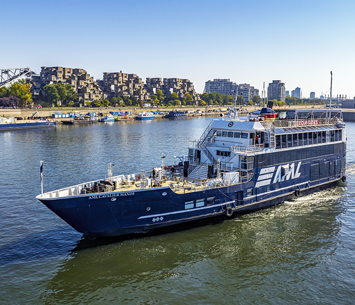 Aerial view of the AML Cavalier Maxim sailing on the St. Lawrence in Montreal, with Habitat 67 in the background.