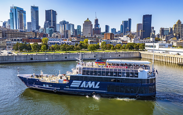 Vue aérienne du navire AML Cavalier Maxim stationné dans le Vieux-Port de Montréal de jour avec vue sur la skyline de la ville en arrière plan.