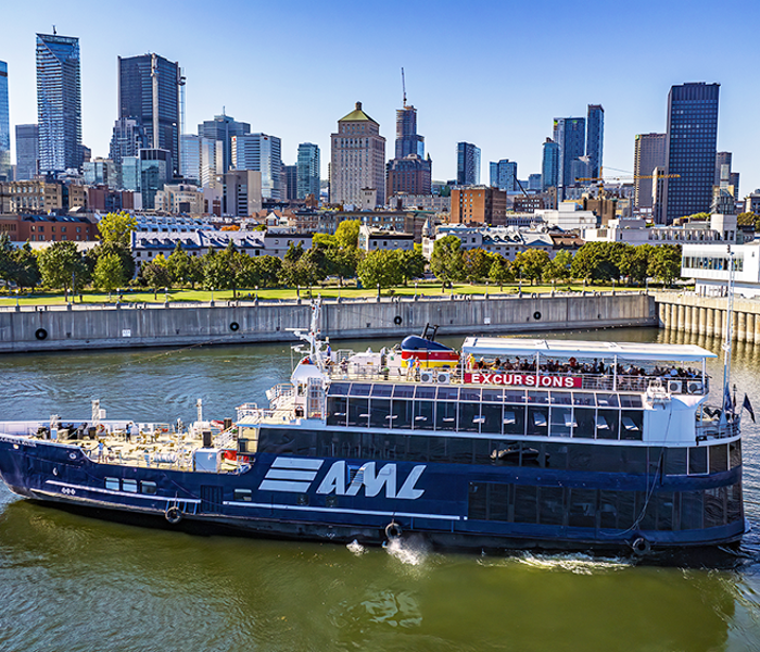 Vue aérienne du navire AML Cavalier Maxim stationné dans le Vieux-Port de Montréal de jour avec vue sur la skyline de la ville en arrière plan.